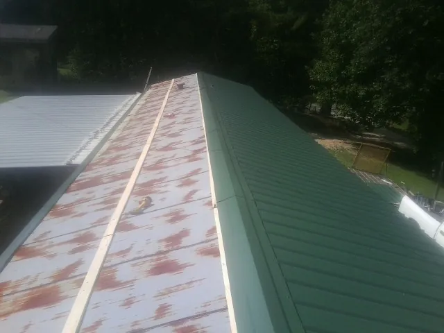 Old rusted panels beside newly installed green metal roofing — Wind Damage Roof Repair by Roofing Brothers in Adkins