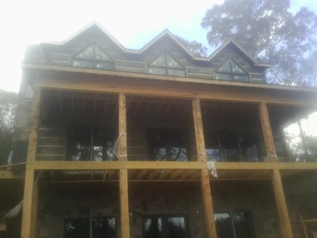 Dormers and porch framing on a large log home under construction — Roof Coating work by our crew in Adkins