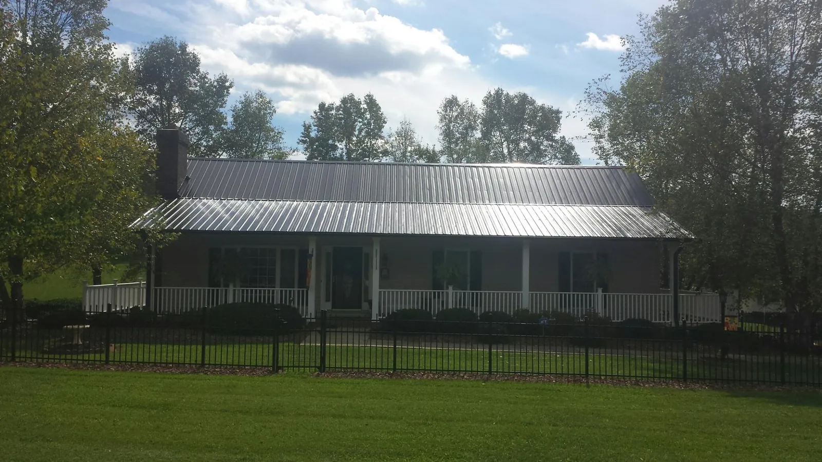 Gray metal roof on a brick ranch with a full width front porch — Gutter Guard Installation work by our crew in Adkins