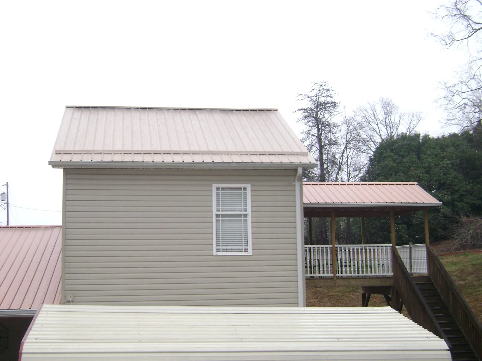 Tan metal roofs on a two story addition and attached porch, from a Roof Replacement job in Adkins