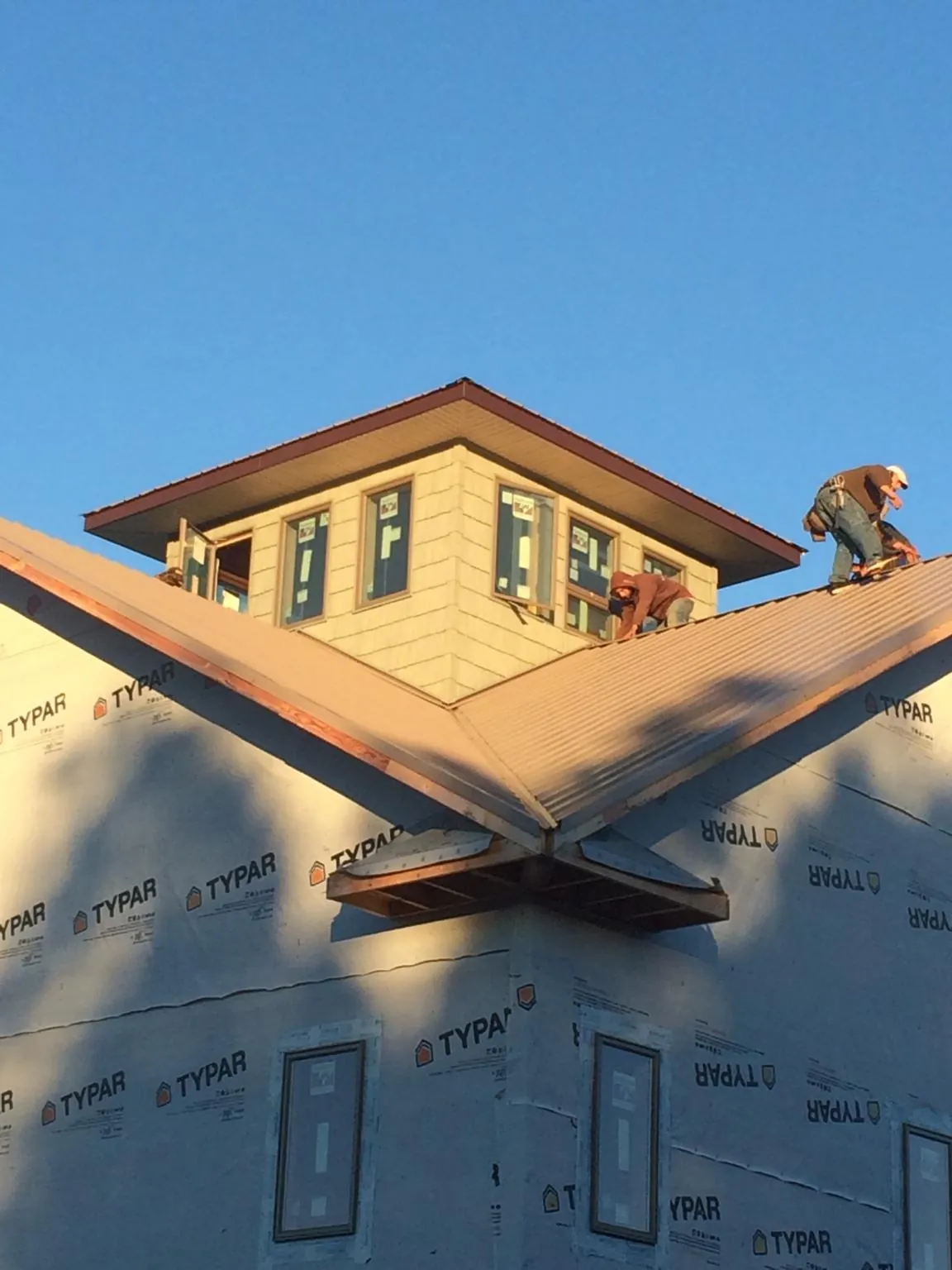 Roofers working around a rooftop cupola on a new metal roof at sunset — Roof Waterproofing in Adkins by Roofing Brothers